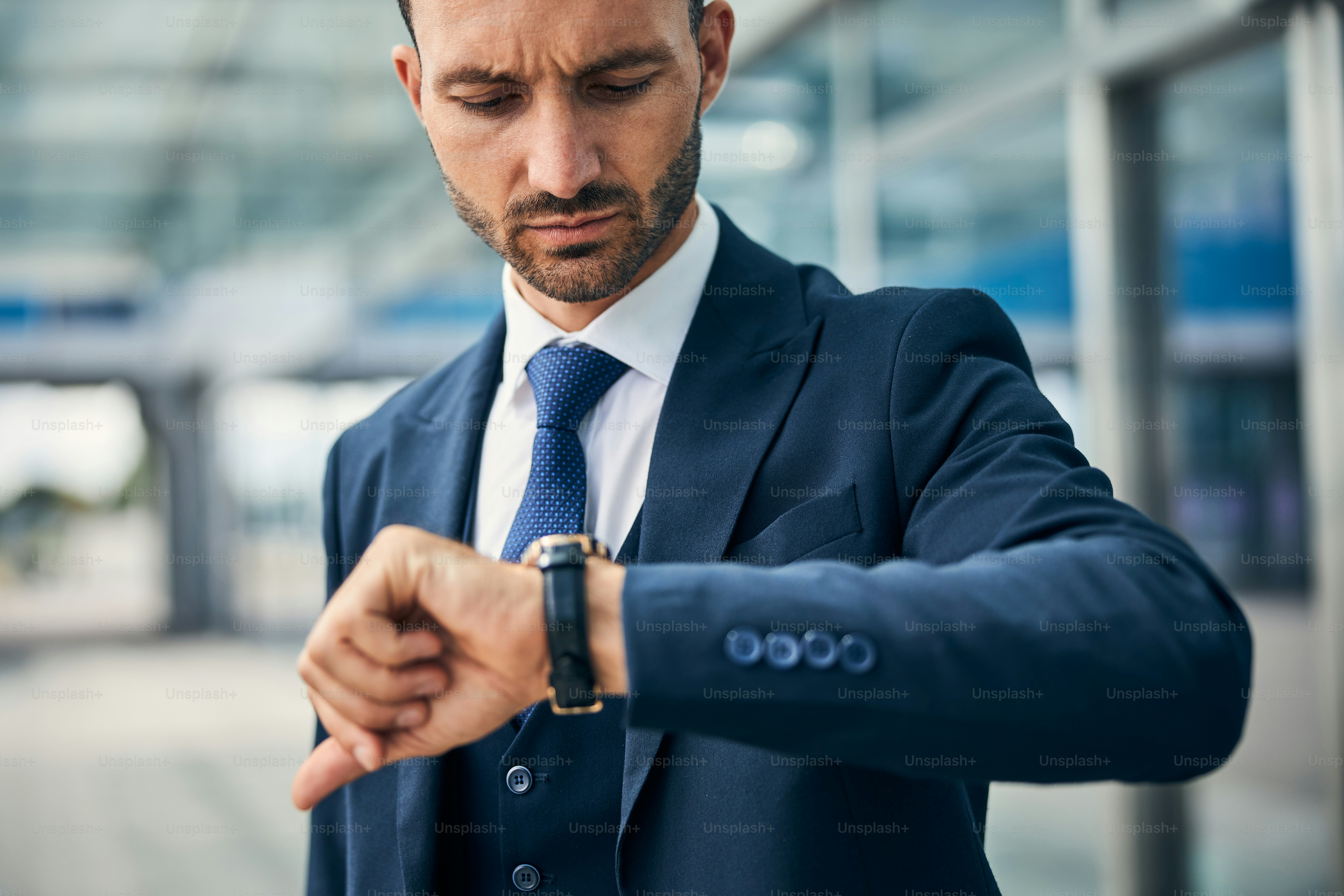 Worried young businessman with a furrowed brow looking at his wrist watch checking the time
