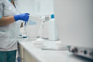 歯科医院の容器に消毒剤を調製する歯科デスクで働く女性の接写画像