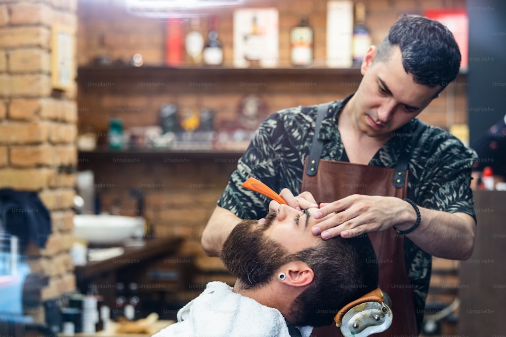 Beard styling and cut. Close up cropped photo of a styling of a beard. So trendy and stylish! Advertising and barber shop concept. Razor in hands of specialist barber