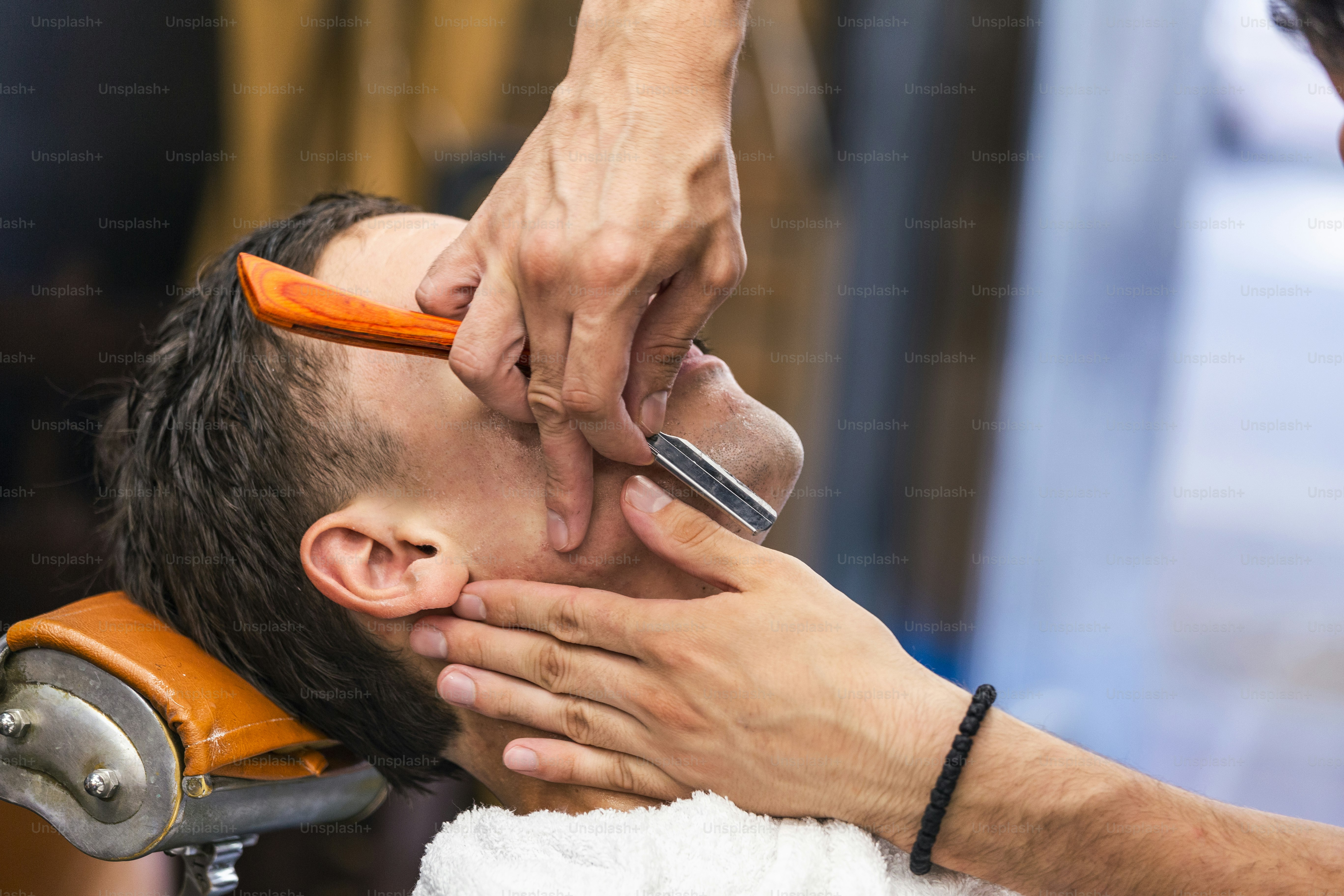 Razor in hands of specialist barber. Barber shaving a man in a barber ...