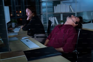 Los empresarios asiáticos tailandeses del centro de llamadas tienen dolor de cabeza y migraña por trabajar en el turno de noche para ayudar a los clientes a asistir en el lugar de trabajo por la noche