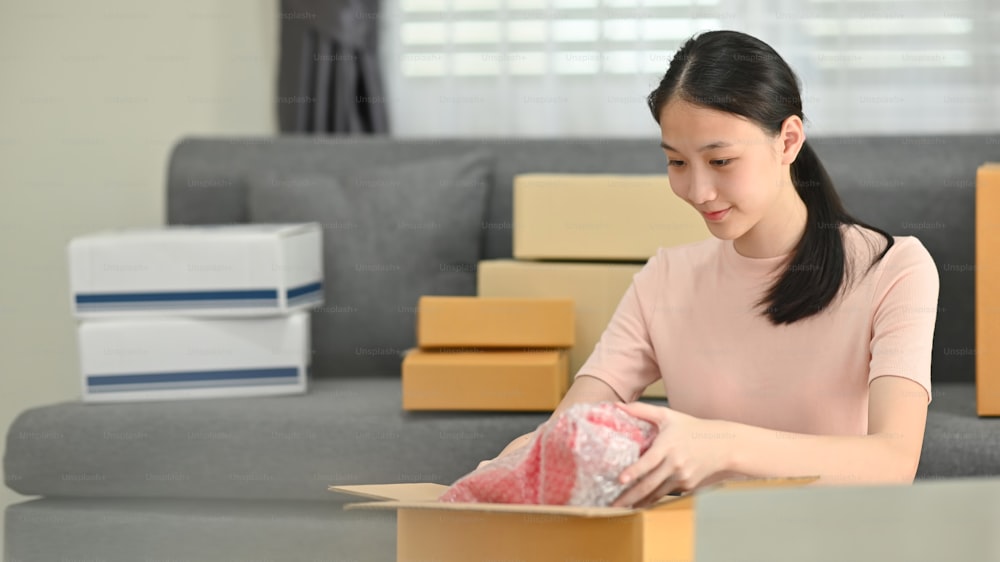 Portrait of young business owner packing box while sitting at the home.