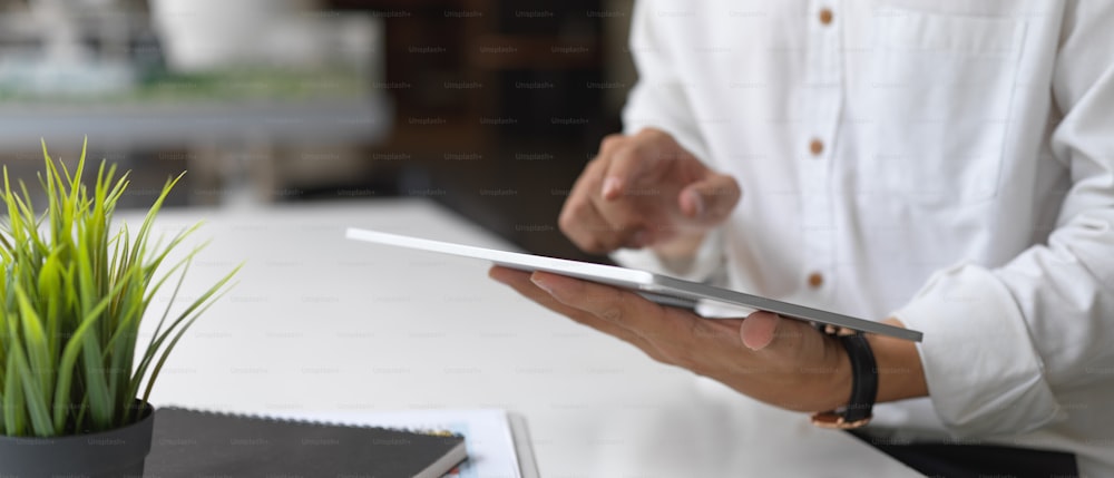 Cropped shot of businessman working on his project with tablet in office room