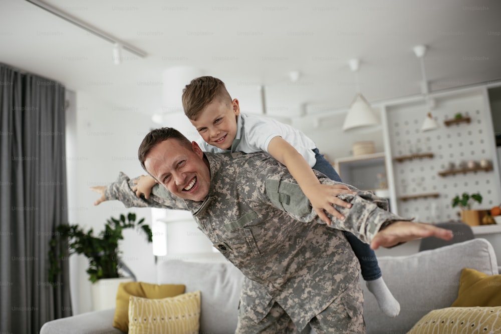 Soldier having fun with his son at home. Father and son playing in living room.