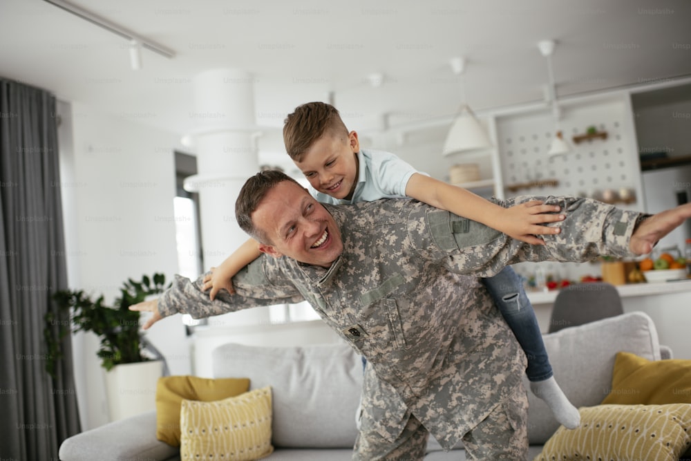 Soldier having fun with his son at home. Father and son playing in living room.