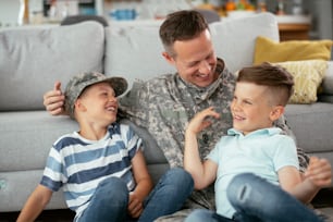 Soldado feliz sentado en el suelo con su familia. Soldado disfrutando en casa con niños.