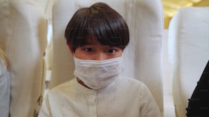 Traveler wearing face mask while traveling on commercial airplane . Concept of coronavirus disease or COVID 19 pandemic outbreak effects on tourism and airline business .