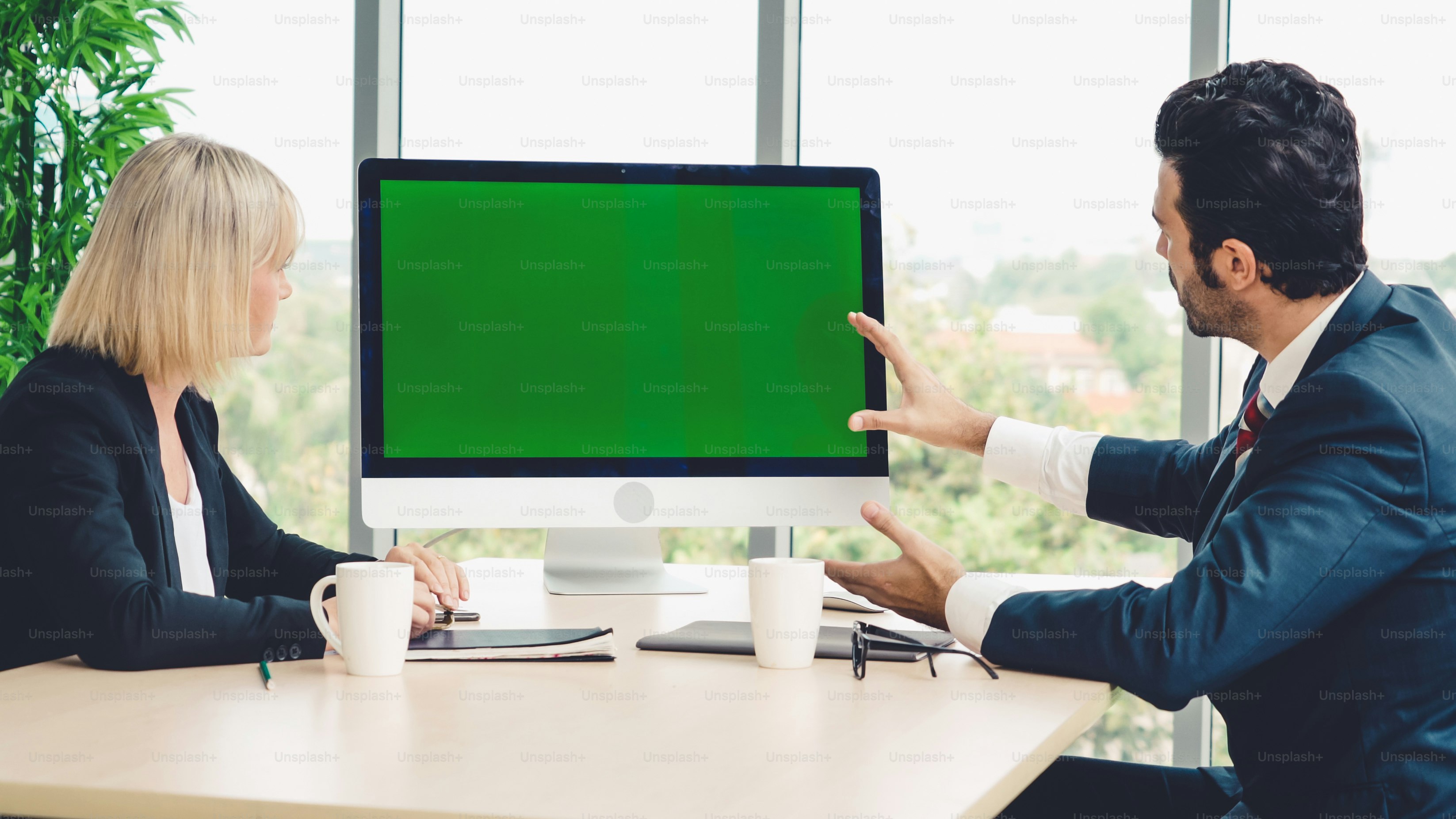 Gente de negocios en la sala de conferencias con pantalla verde chroma key TV o computadora en la mesa de la oficina. Grupo diverso de hombres y mujeres de negocios en reunión en videoconferencia.