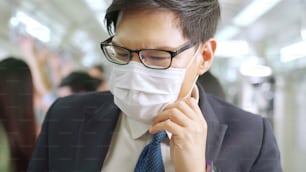 Young man wearing face mask travels on crowded subway train . Coronavirus disease or COVID 19 pandemic outbreak and urban lifestyle problem in rush hour concept .