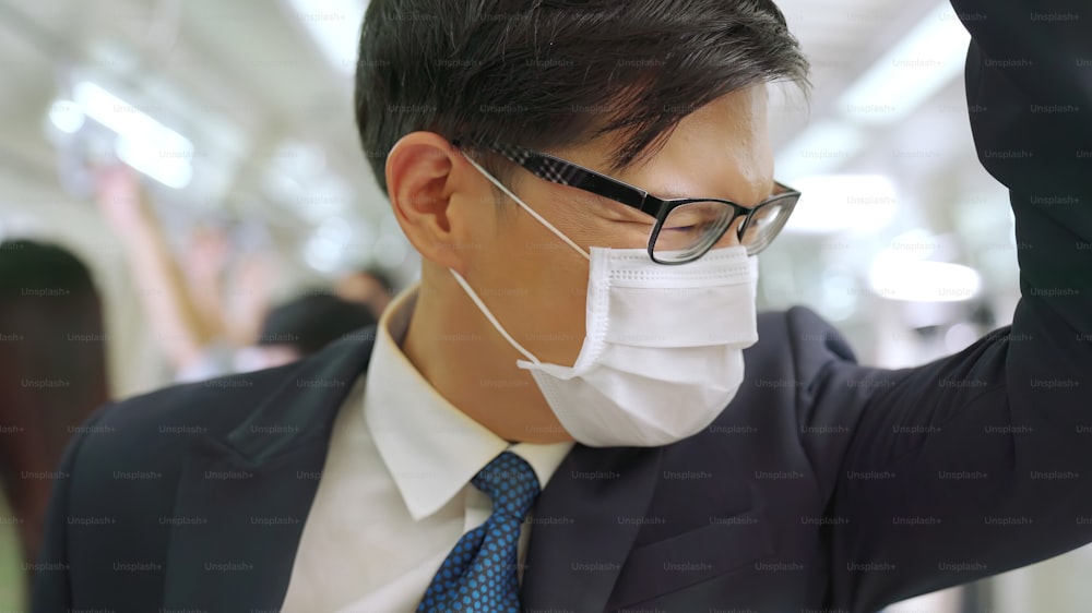 Young man wearing face mask travels on crowded subway train . Coronavirus disease or COVID 19 pandemic outbreak and urban lifestyle problem in rush hour concept .