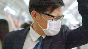 マスクを着けた若い男性が満員の地下鉄で移動します。コロナウイルス病またはCOVID19パンデミックの発生とラッシュアワーのコンセプトにおける都市ライフスタイルの問題。