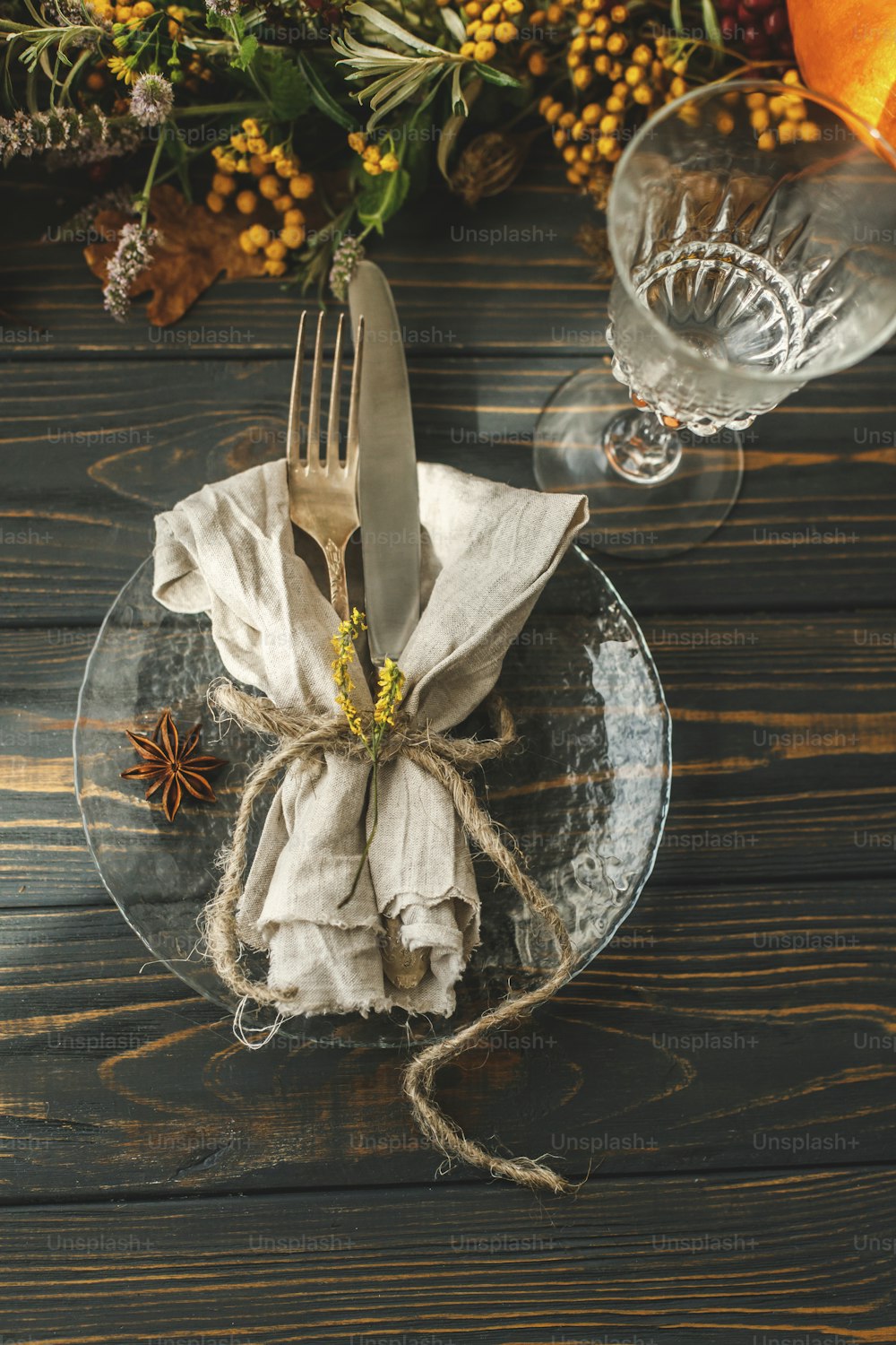 Thanksgiving-Tischdekoration. Stilvoller Teller mit Besteck und Herbstdekoration, Kürbis, Naturzweigen und herbstlichen Blumen auf rustikalem Tisch. Hochzeitscatering im Herbst
