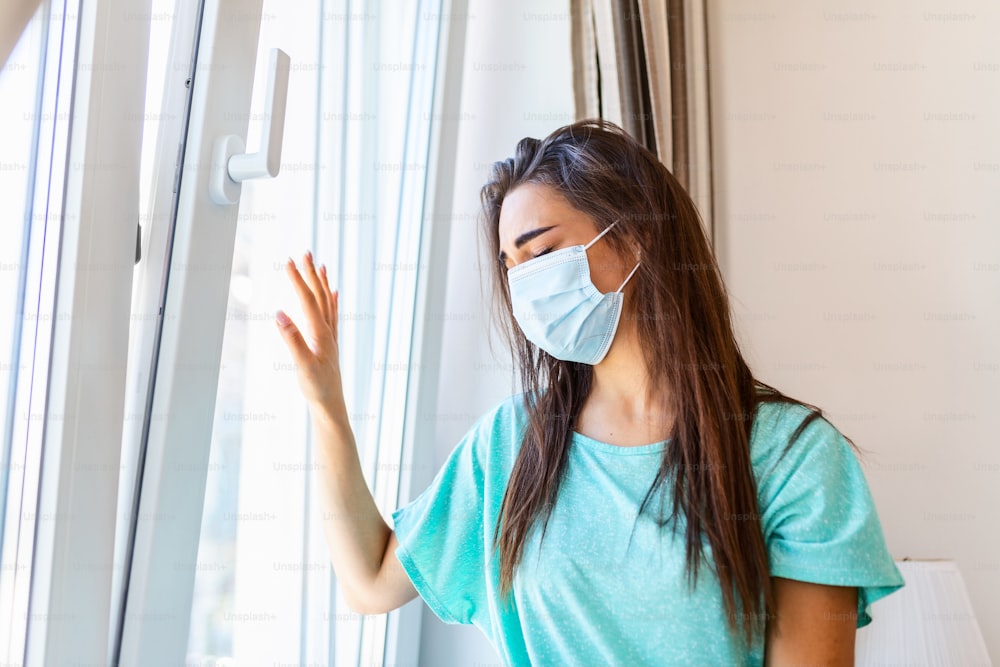 Junge Frauen mit medizinischer Maske bleiben zu Hause isoliert und befinden sich in Selbstquarantäne. Konzept häusliche Quarantäne, Prävention COVID-19, Coronavirus-Ausbruchssituation
