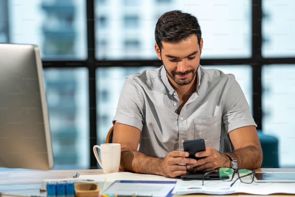 Portrait of Smiling Caucasian man office worker using smartphone with internet in modern office