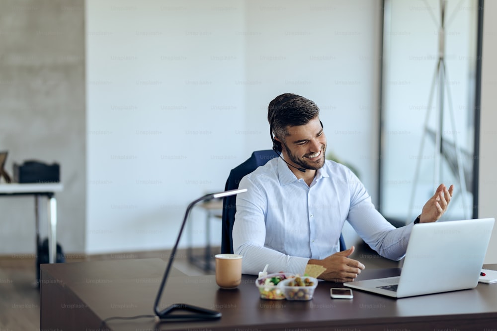 Young happy businessman using computer while having conference call in the office.