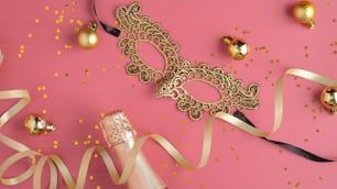 Christmas party background with streamers, champagne bottle, golden ball decorations, masquerade mask. Flat lay, top view.