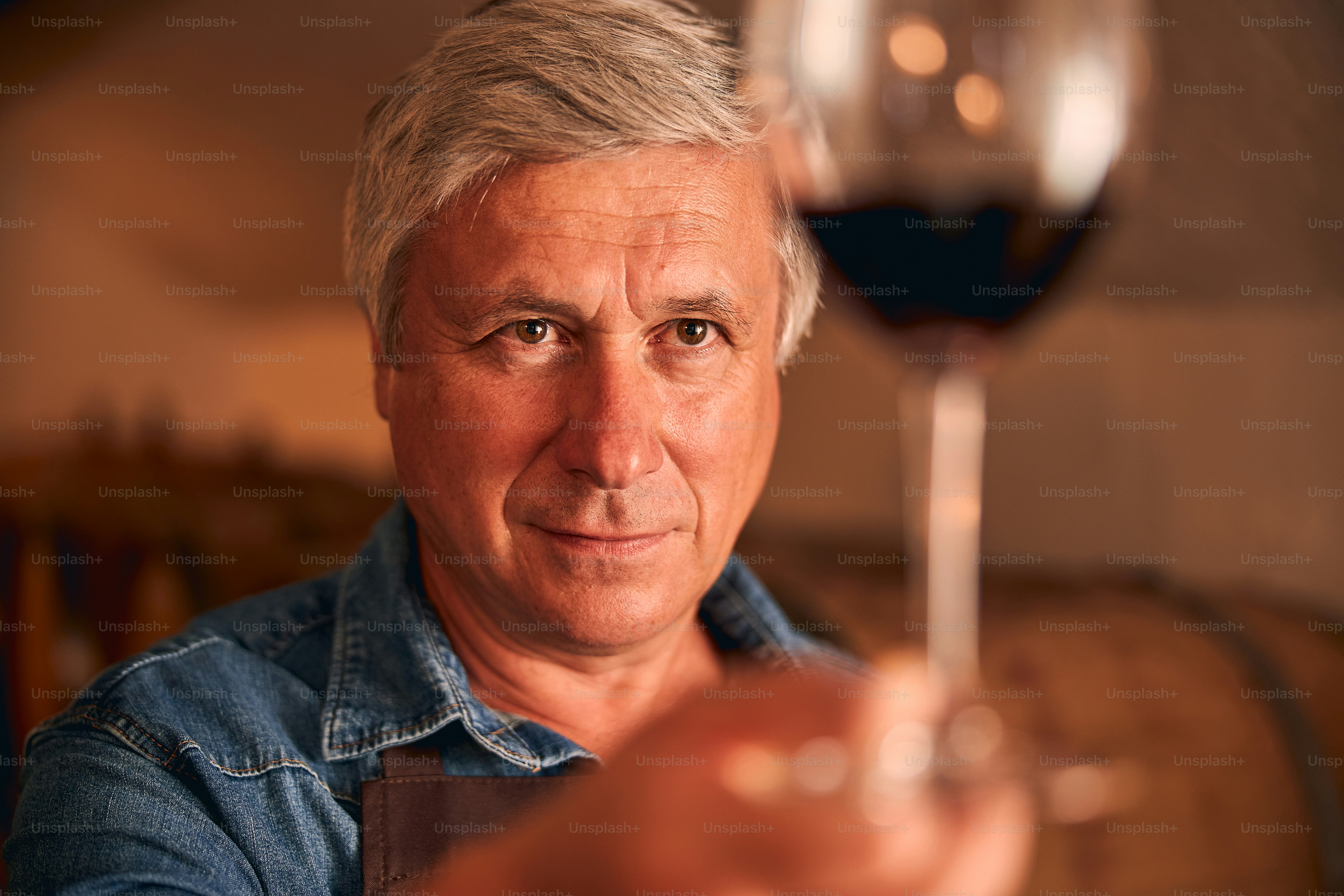 Primer plano del enólogo masculino mirando un vaso de bebida alcohólica en su mano