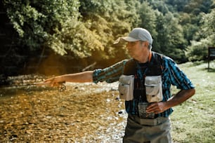 Senior man is fishing alone on fast mountain river. Active people and sport fly fishing concept.