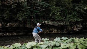 O homem idoso está pescando sozinho no rio da montanha rápida. Pessoas ativas e conceito de pesca com mosca esportiva.