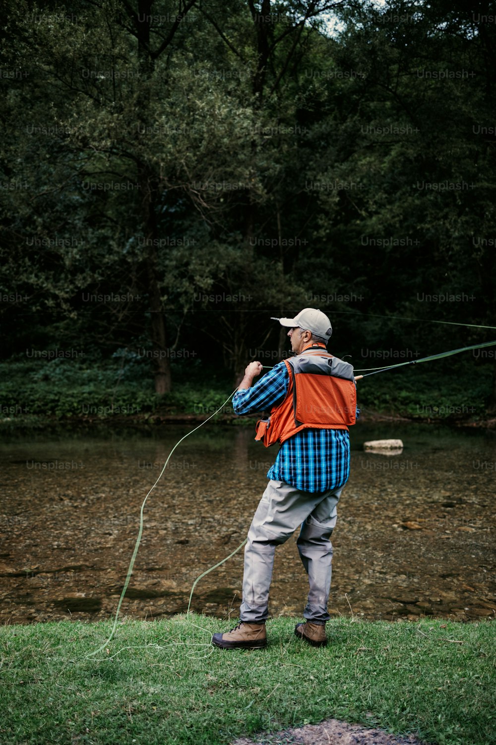 Un hombre mayor está pescando solo en un río de montaña rápido. Concepto de pesca con mosca de personas activas y deportivas.