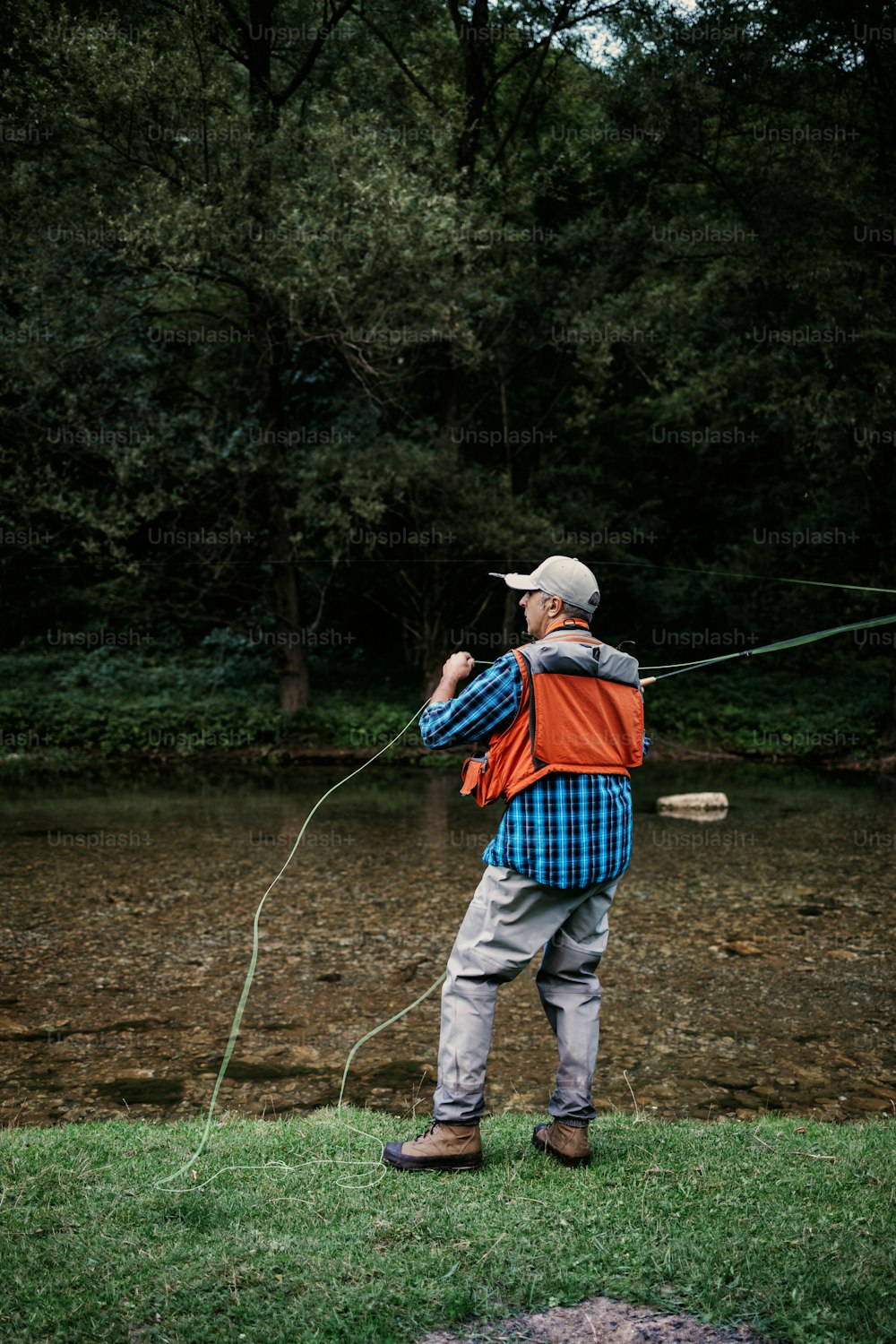 Senior man is fishing alone on fast mountain river. Active people and sport fly fishing concept.