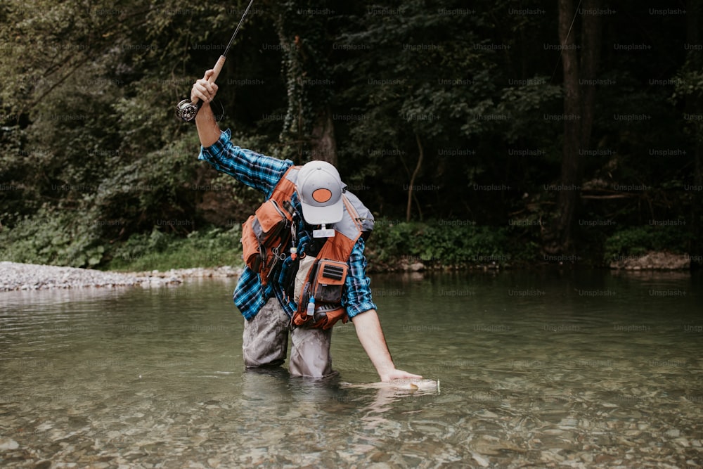 Un homme âgé pêche seul sur une rivière de montagne rapide. Il tient une truite vivante et l’embrasse avant de la relâcher à nouveau dans la rivière.