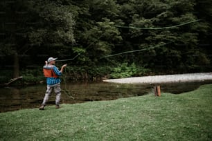 O homem idoso está pescando sozinho no rio da montanha rápida. Pessoas ativas e conceito de pesca com mosca esportiva.