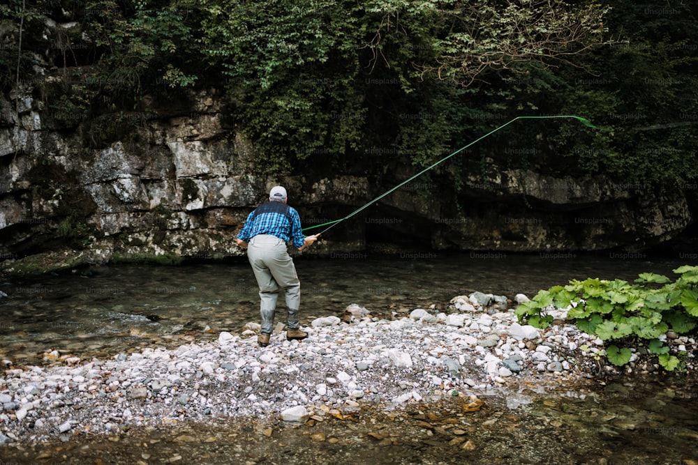 Un hombre mayor está pescando solo en un río de montaña rápido. Concepto de pesca con mosca de personas activas y deportivas.