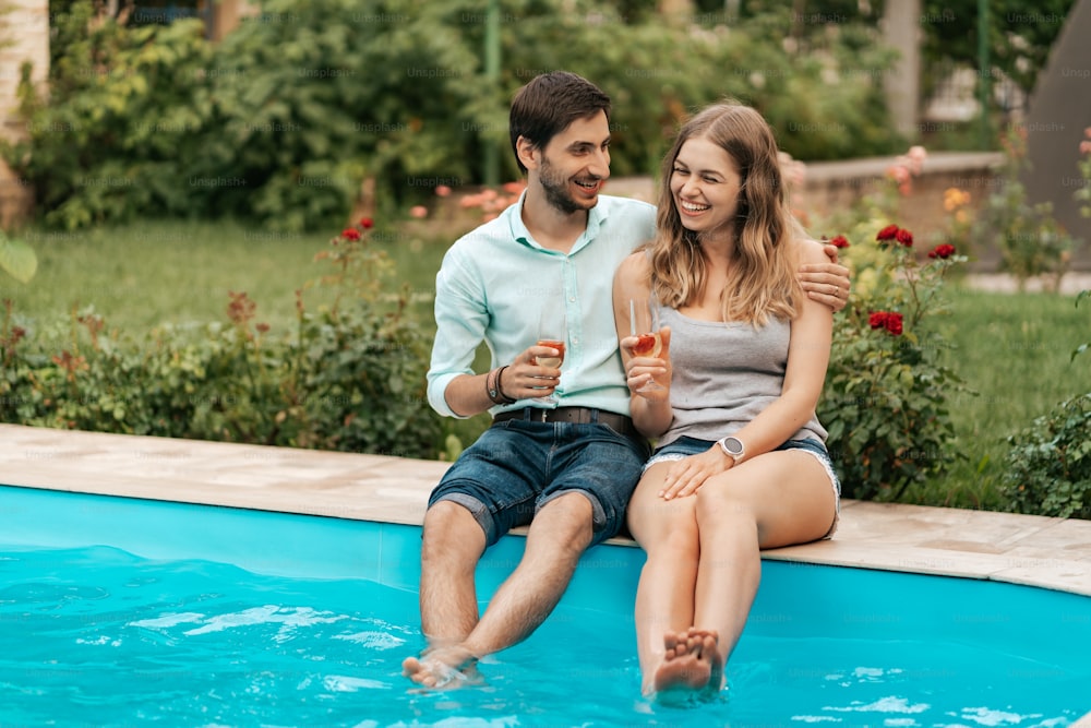 Férias de verão, pessoas, romance, conceito de namoro, casal bebendo vinho espumante enquanto desfrutam do tempo juntos sentados na piscina