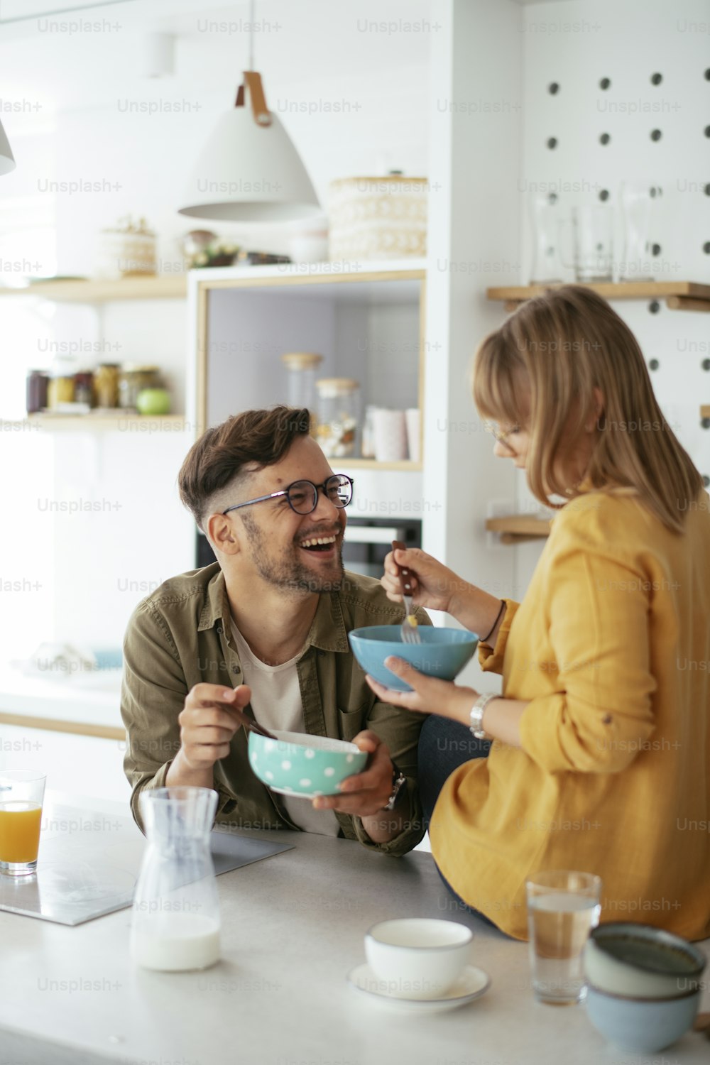 Jovem casal fazendo café da manhã em casa. Casal amoroso comendo cereais na cozinha.