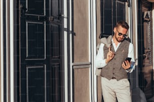 Portrait of a young corporate businessman using a smartphone and wearing sunglasses