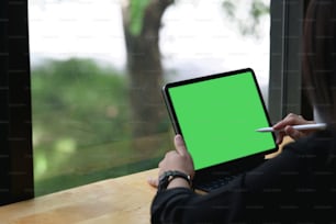 Closeup woman using stylus pen on green screen of digital tablet.