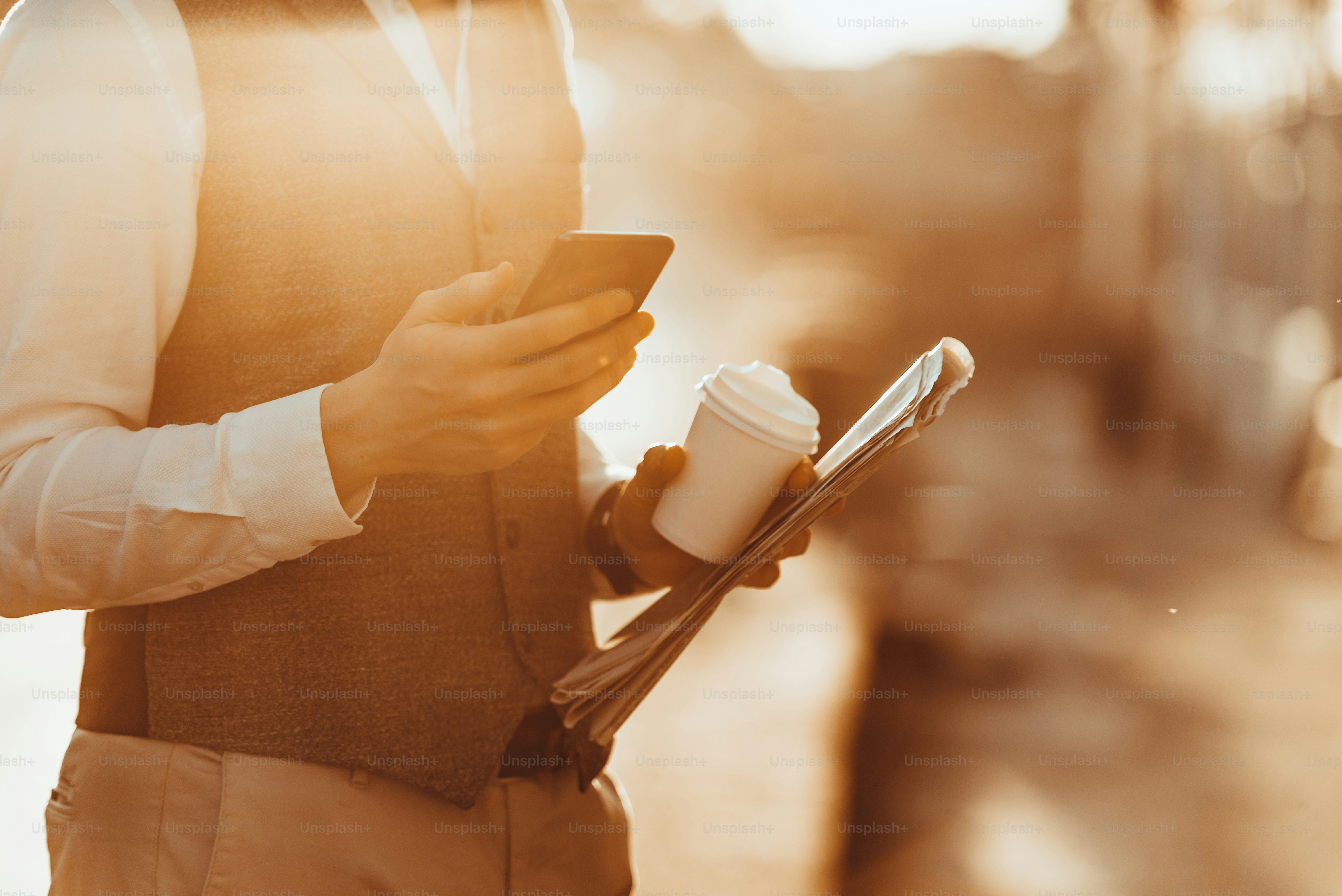 Cropped shot of a handsome young businessman in a suit dressed to succeed while drinking coffee and using smartphone