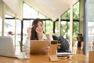 Beautiful confident woman looking at her tablet concentrate on it while sitting.