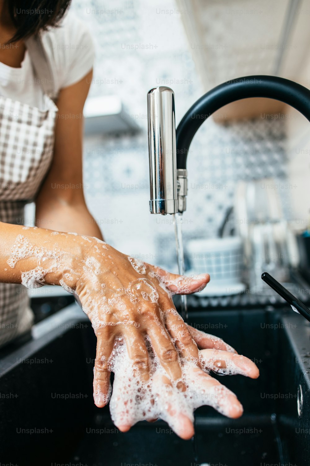 Giovane donna adulta che si lava le mani sul lavandino della cucina. Routine di igiene domestica e domestica e personale.