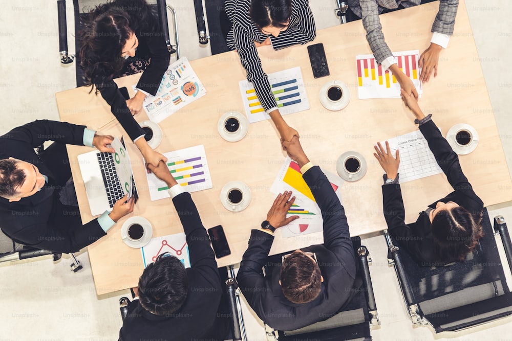 Group business people handshake at meeting table in office together with confident shot from top view . Young businessman and businesswoman workers express agreement of investment deal.