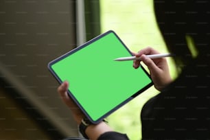 Female hand using digital drawing tablet with green screen in her office.