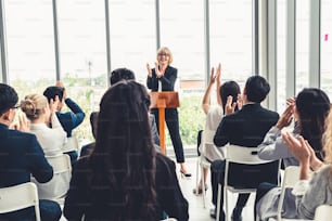 Group of business people meeting in a seminar conference . Audience listening to instructor in employee education training session . Office worker community summit forum with expert speaker .