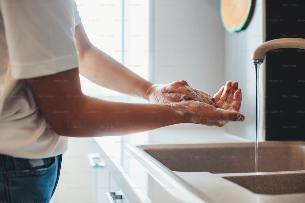 Side view photo of a caucasian man washing his hands in the kitchen with soap