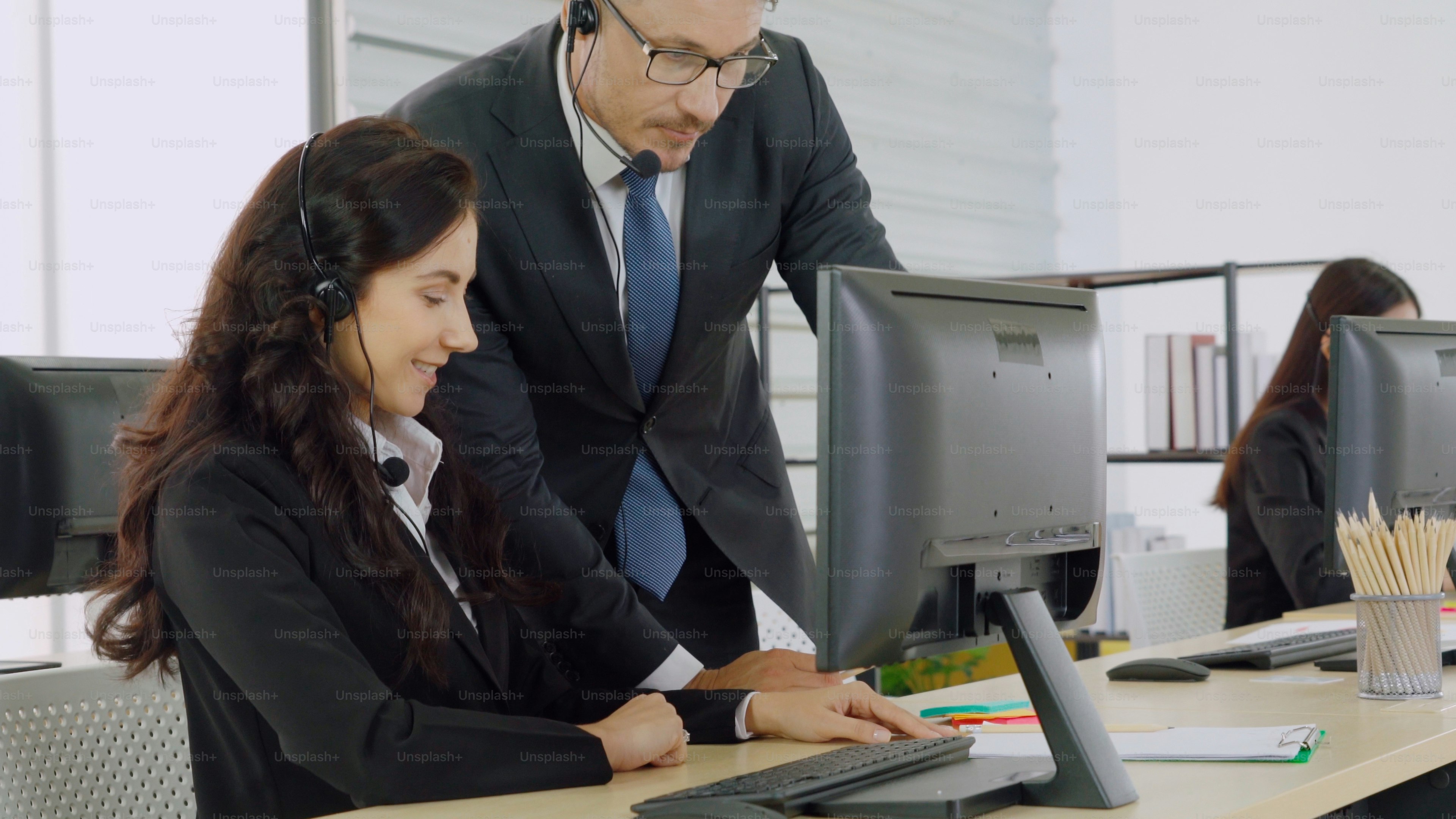 Business people wearing headset working in office to support remote customer or colleague. Call center, telemarketing, customer support agent provide service on telephone video conference call.