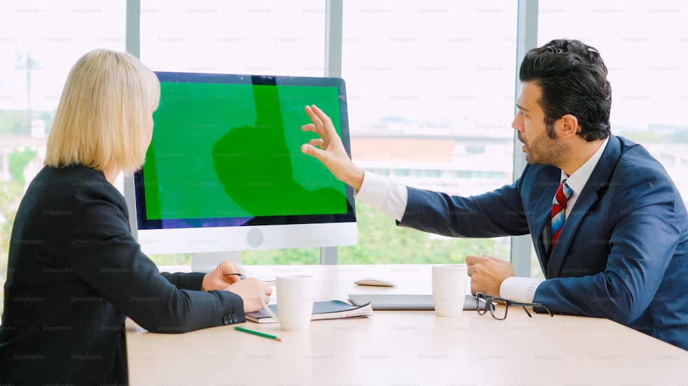 사무실 테이블에 녹색 스크린 크로마 키 TV 또는 컴퓨터가 있는 회의실의 비즈니스 사람들. 화상 회의에서 만나는 사업가와 사업가의 다양한 그룹.