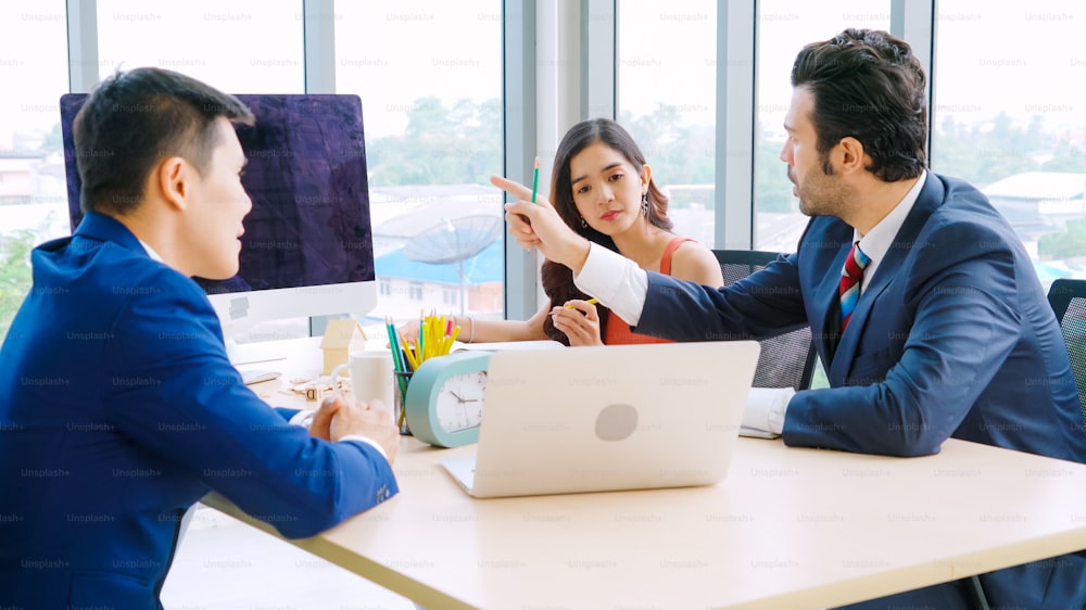 Smart businessman and businesswoman talking discussion in group meeting at office table in a modern office interior. Business collaboration strategic planning and brainstorming of coworkers.