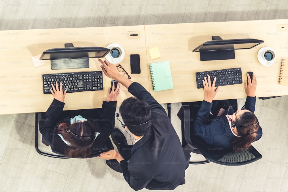 Geschäftsleute, die Headsets aus der Draufsicht im Büro tragen, arbeiten mit Computern, um entfernte Kunden oder Kollegen zu unterstützen. Callcenter, Telemarketing-Agentenservice per Telefon oder Videokonferenz.