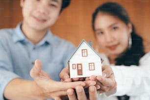 Young couple showing house model. Real estate, buy or sale or moving home or renting property. Mortgage and business concept.