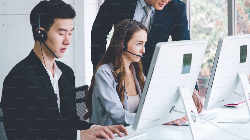 Business people wearing headset working in office to support remote customer or colleague. Call center, telemarketing, customer support agent provide service on telephone video conference call.