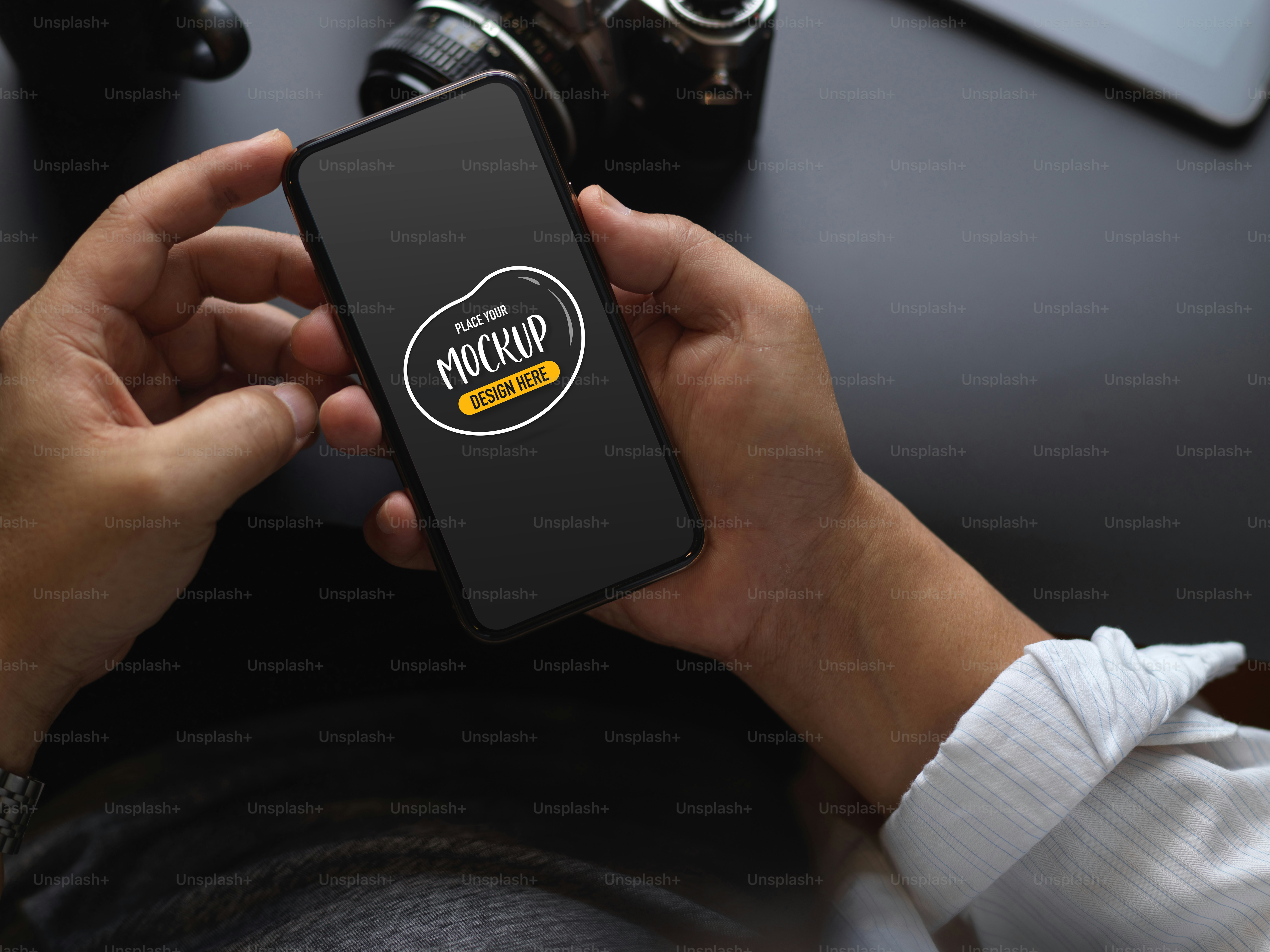 Foto pekerja laki-laki yang dipotong menggunakan smartphone mock up saat bekerja di meja hitam