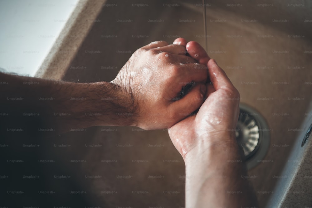 Upper view photo of a caucasian man washing his hands with soap during the epidemic situation