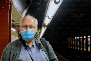 지하철 코로나 바이러스 전염병에 서있는 의료 마스크를 쓴 노인이 기차 지하철을 기대합니다.