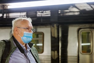 Covid-19地下鉄駅の顔使い捨てマスクの男電車の地下鉄チューブ男性のヘルスケアソフトフォーカス列車でのコロナウイルスの流行パンデミック