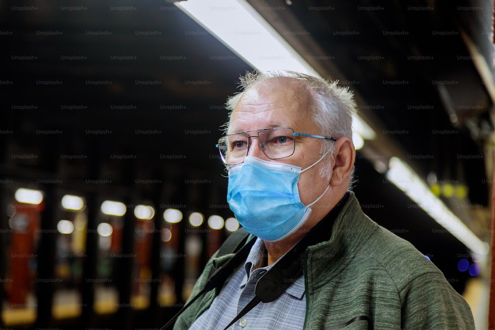 Safety in a public place while epidemic mature man wearing disposable medical face mask of the subway in New York during coronavirus outbreak of covid-19.